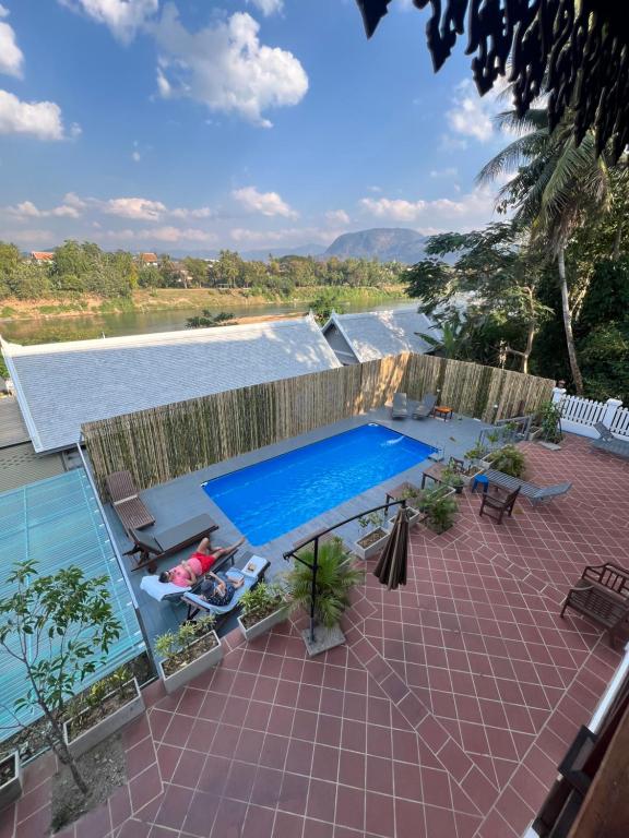 a woman sitting in a chair next to a swimming pool at Namkhan Riverview Boutique House in Luang Prabang