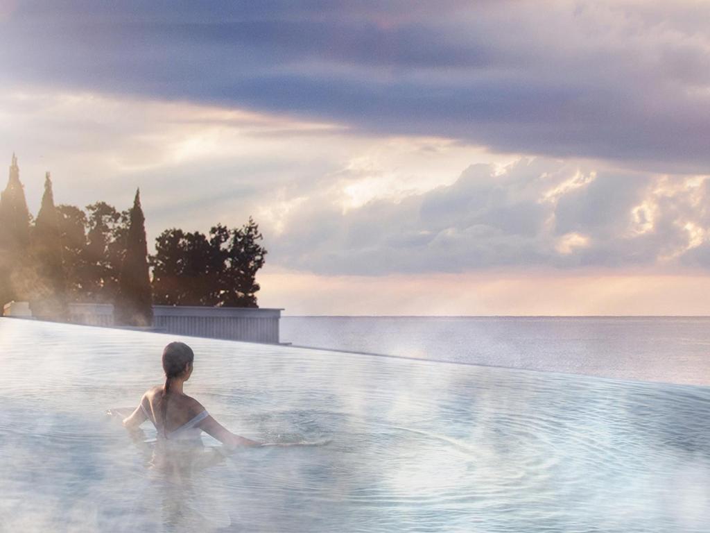 a woman is standing in a bath tub in the water at The Siena Resort in Seogwipo