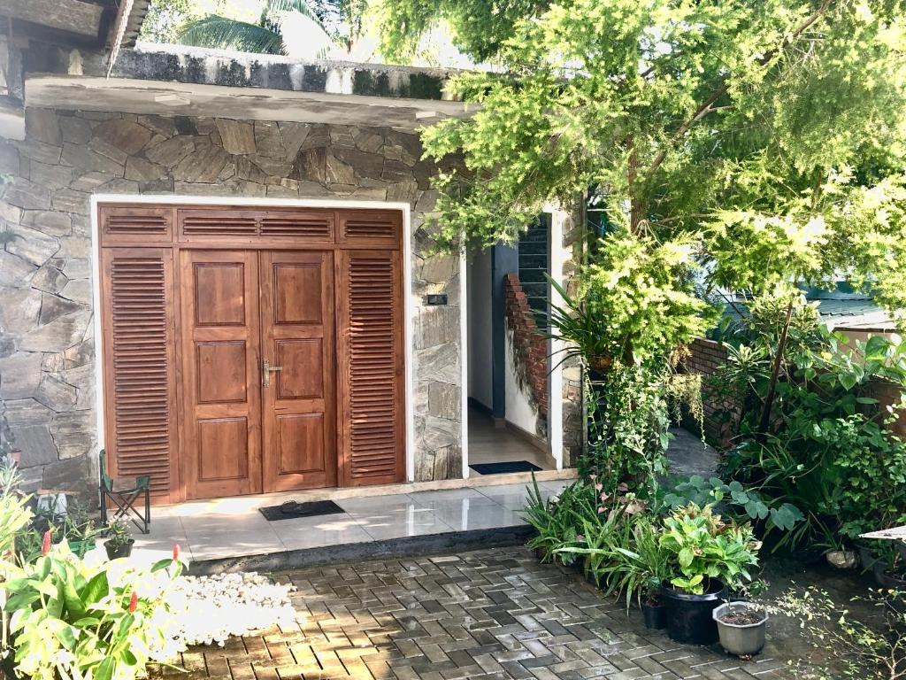 uma porta de madeira numa casa de pedra com plantas em SERENE HOME em Kandy