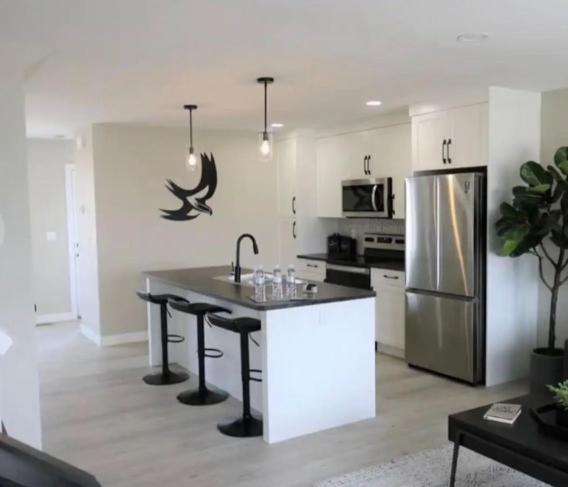 a kitchen with a island with a sink and a refrigerator at New Townhouse in Red Deer in Red Deer