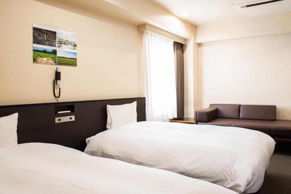 a hotel room with two beds and a couch at Hotel Continental Fuchu in Fuchu