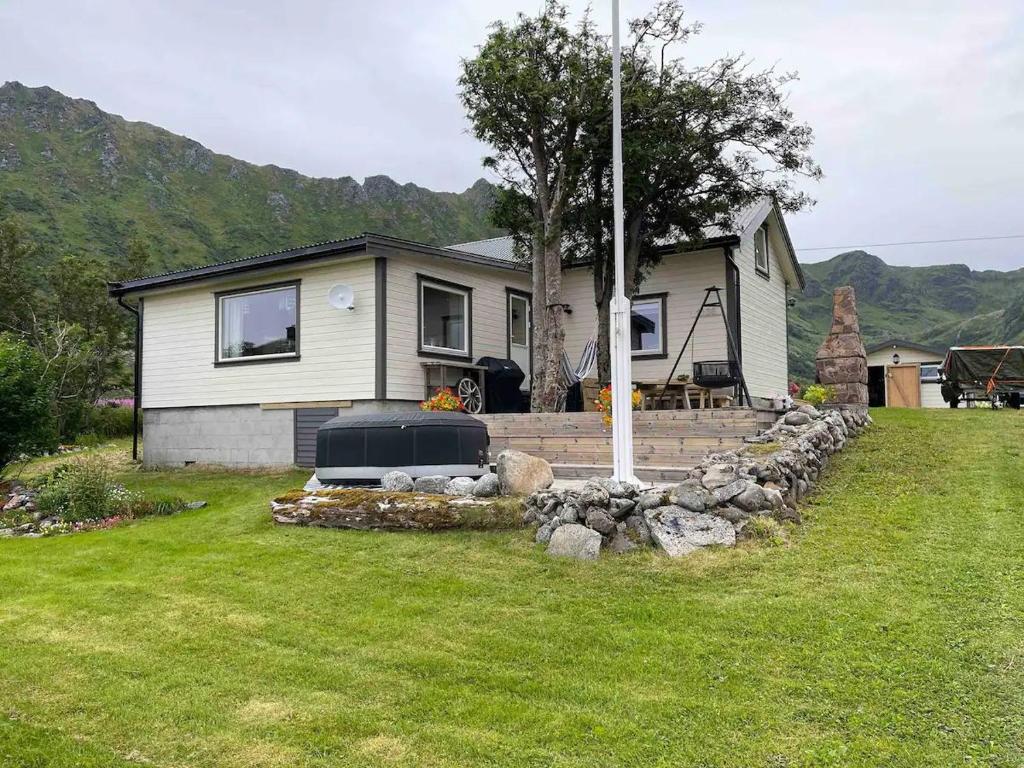 a house with a stone retaining wall in a yard at Paradis i Brenna, Lofoten in Kleppstad