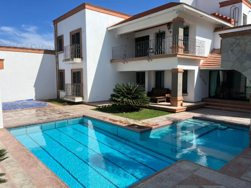 a villa with a swimming pool in front of a house at Cara relax & nature in Tequisquiapan