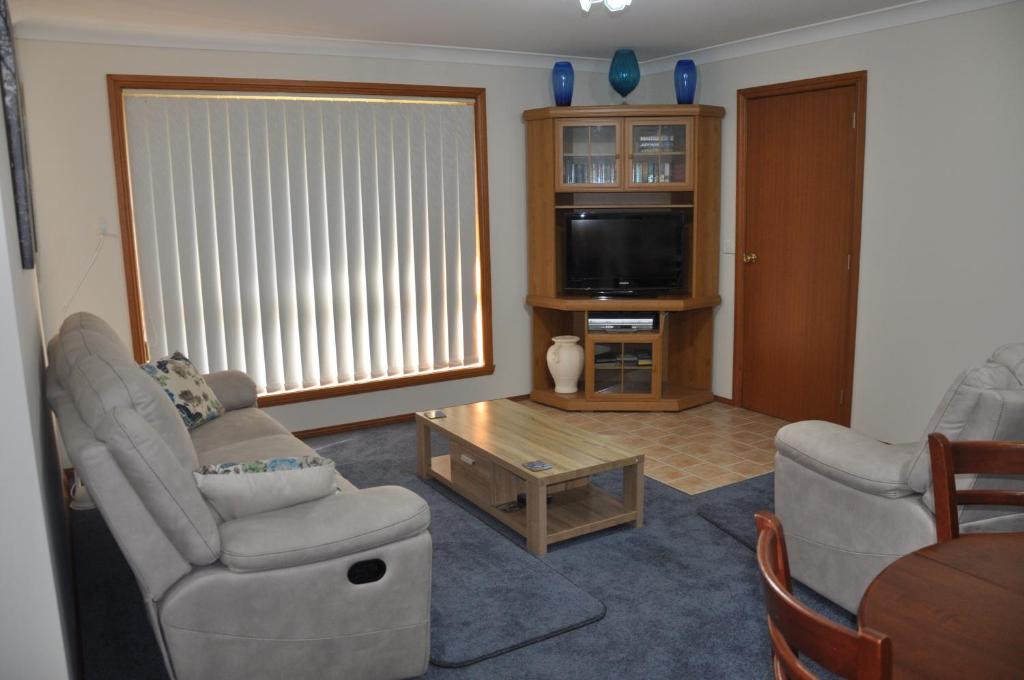 un soggiorno con 2 sedie e una TV di Blue Wren Cottage a Tumut