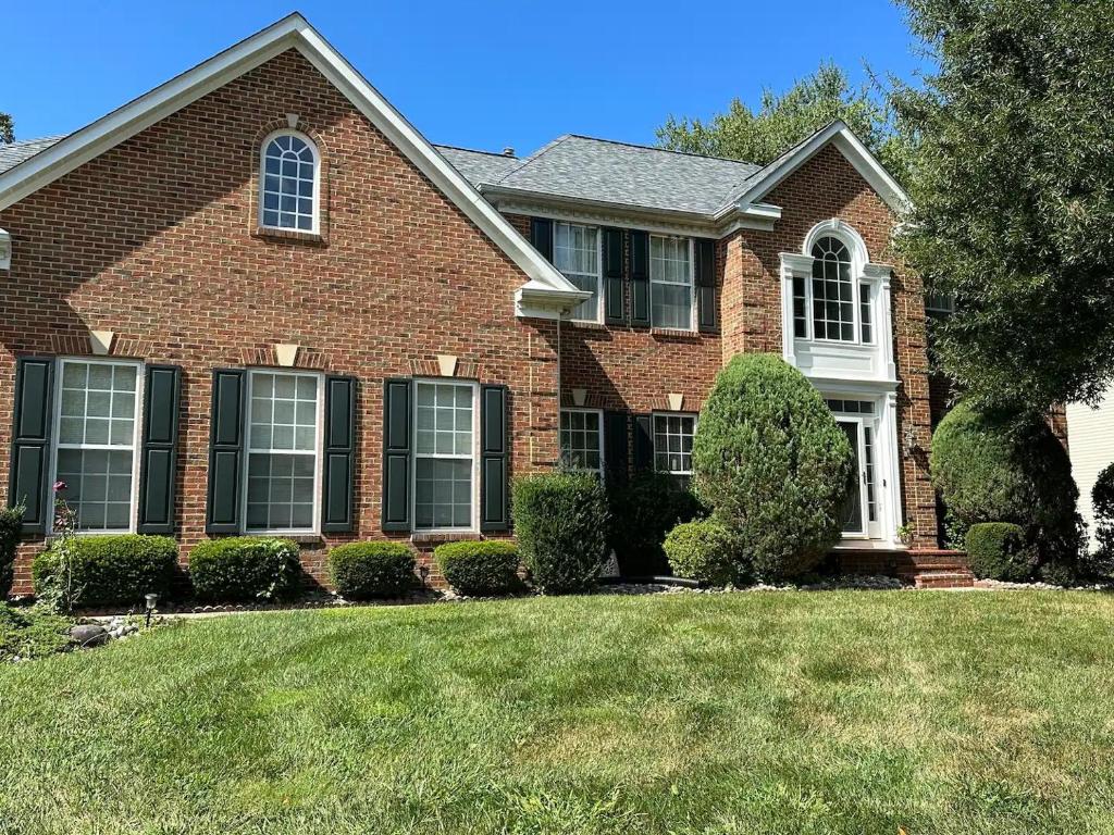a brown brick house with a grass yard at The Oasis@Woodyard in Upper Marlboro