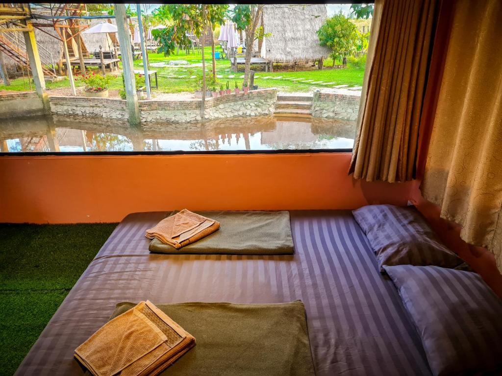 a bedroom with two beds and a large window at Steng Toch Homestay in Phumĭ Bântéay Srei