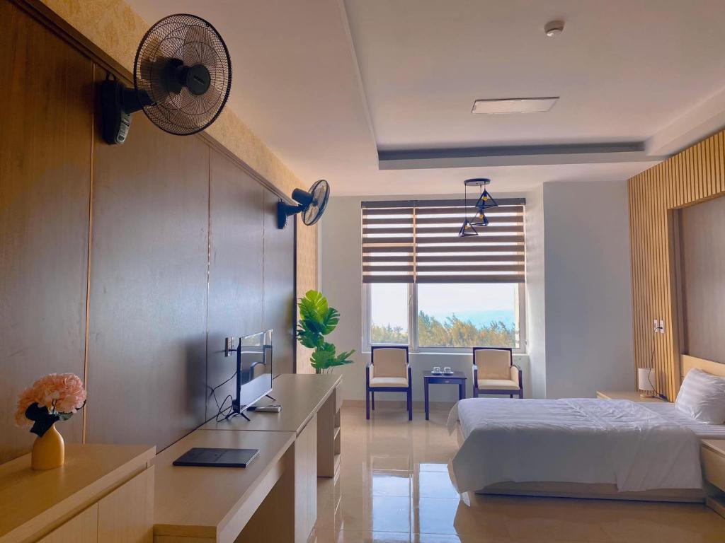 Schlafzimmer mit einem Bett und einem Schreibtisch mit einem Ventilator in der Unterkunft Khách sạn 20-10 Quảng Bình in Dong Hoi