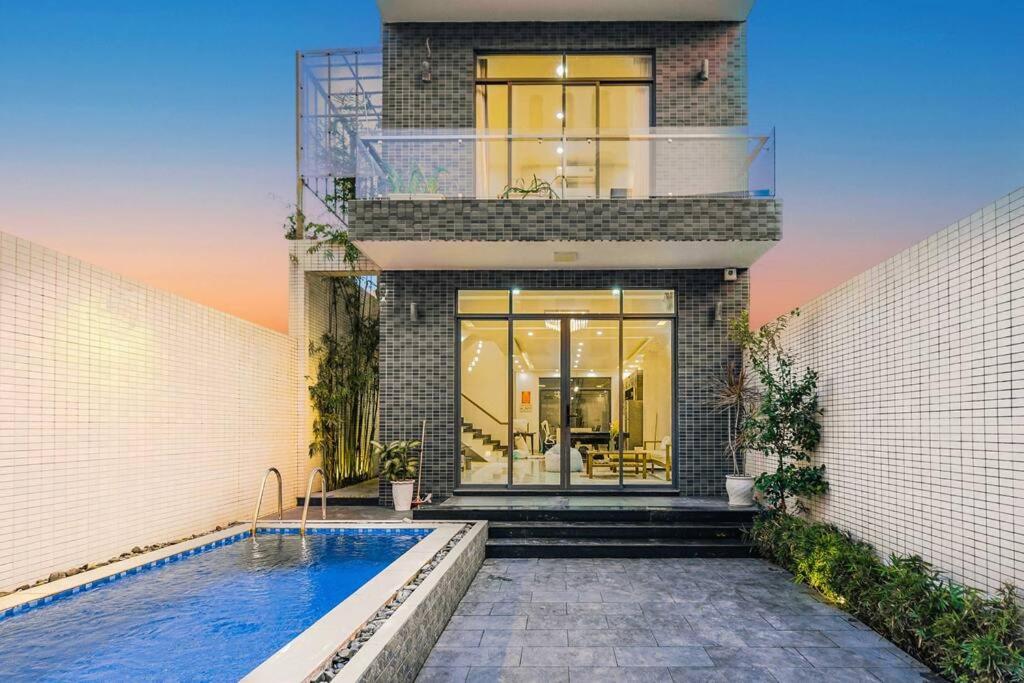 une maison avec une piscine en face de celle-ci dans l'établissement Sunset Pool Villa 4BR, New, Full AC, walk to beach, à Đà Nẵng