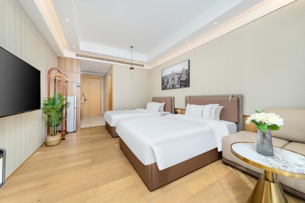 Cette chambre comprend 2 lits et une télévision. dans l'établissement East Maple International Apartment - Guangzhou International Financial City Keyun Road Metro Station, à Canton