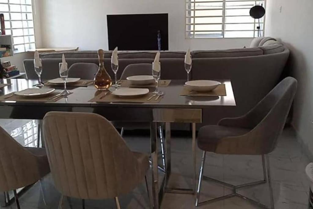 a dining room with a table with chairs and a couch at Chateau Eyram in Accra