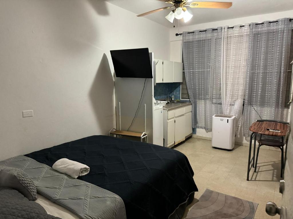 a bedroom with a black bed and a kitchen at Economical Near Beach with Full bed 4th floor in San Juan
