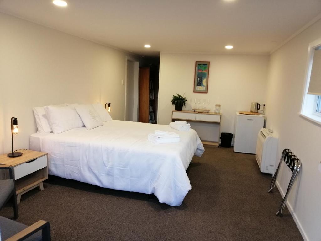 um quarto com uma grande cama branca e uma secretária em Reeves Retreat-Handy in Tasman em Nelson