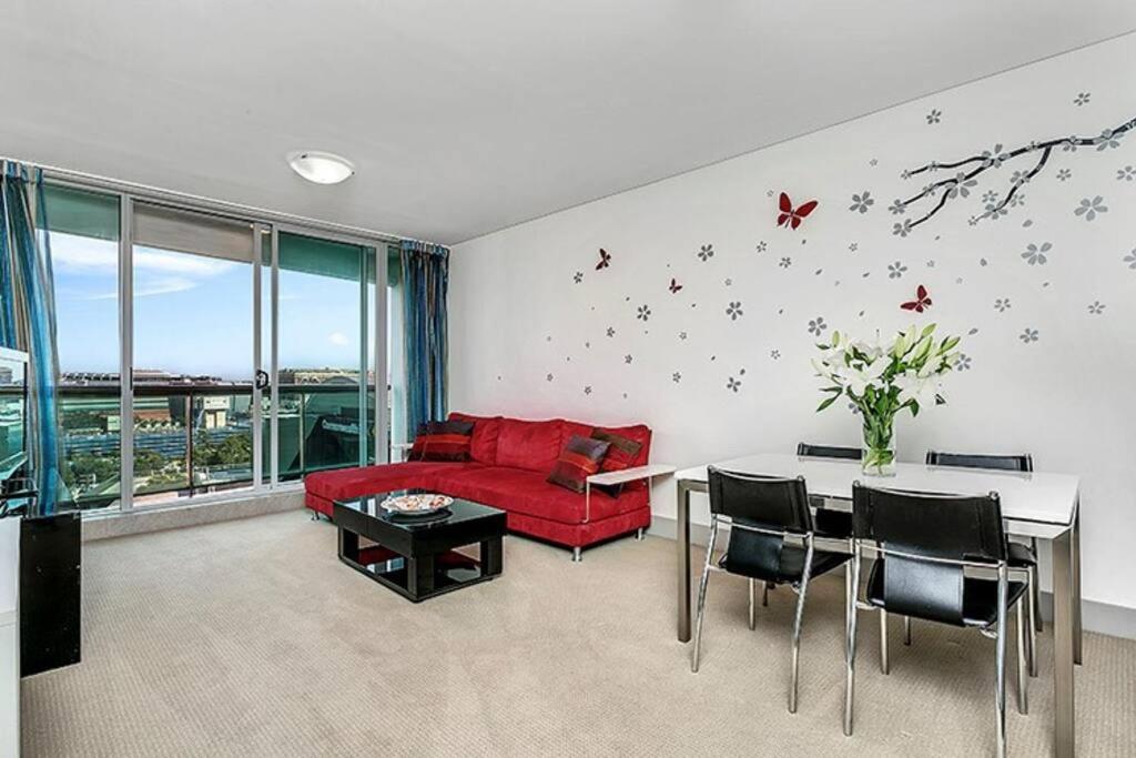 a living room with a red couch and a table at CBD Chinese Gardens Views, Modern 2BR Apt SX339 in Sydney