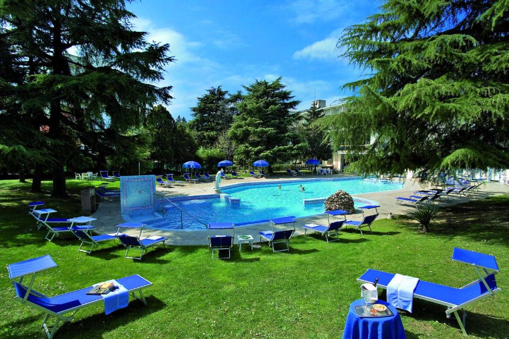 a large swimming pool with blue chairs and umbrellas at Hotel Terme Bologna in Abano Terme