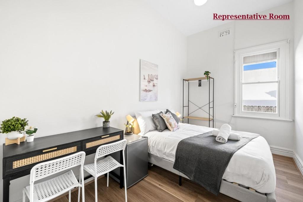 um quarto com uma cama, uma secretária e cadeiras em Premier Leichhardt Stayz em Sydney