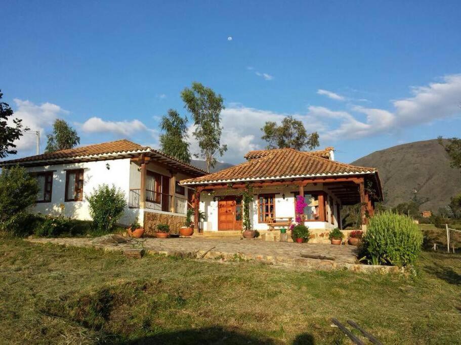 una pequeña casa blanca con una montaña en el fondo en Casa campestre - Villa de Leyva, en Villa de Leyva