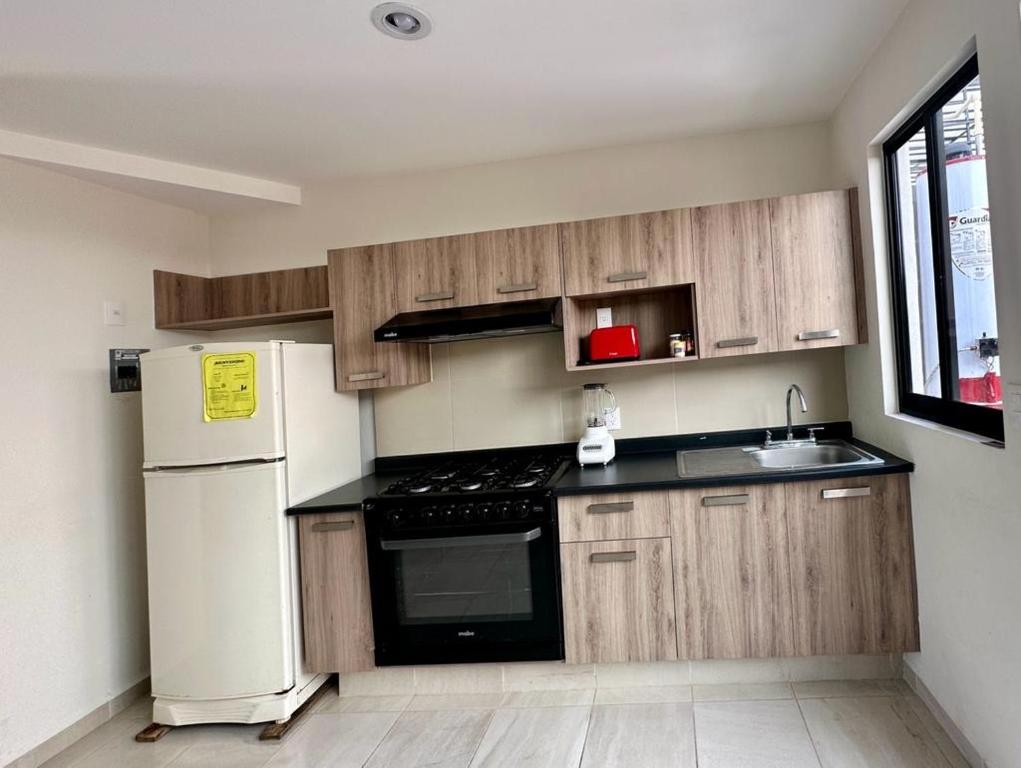 una cucina con armadi in legno e frigorifero bianco di Alojamiento completo a San Isidro de los López