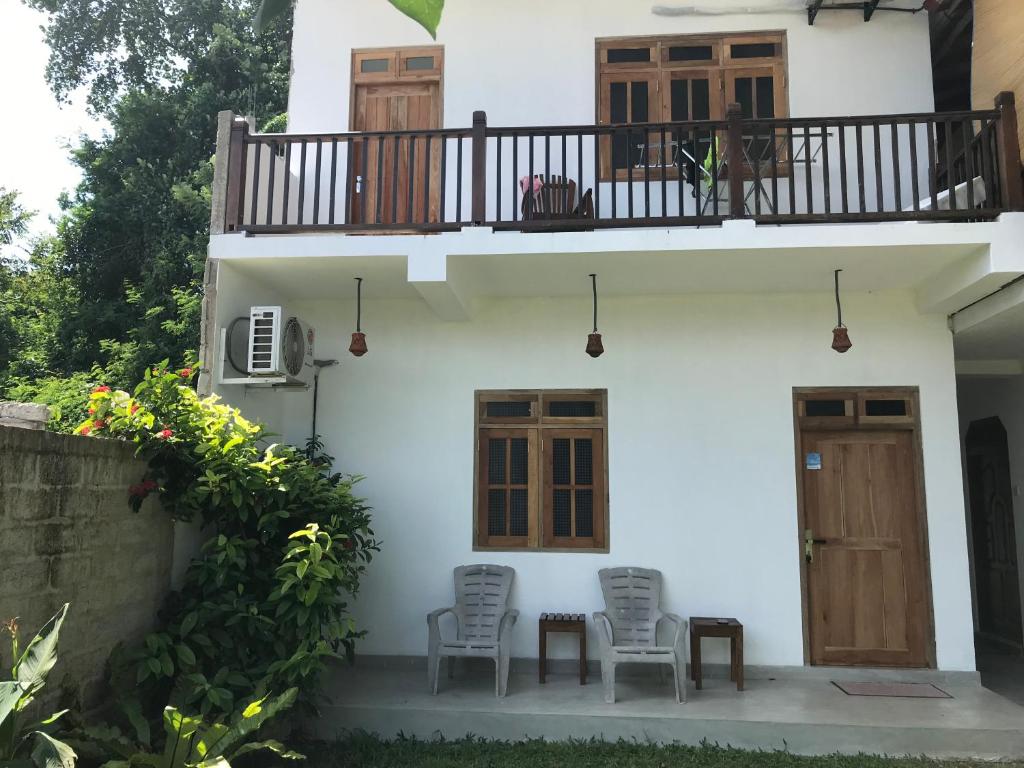 a white house with two chairs and a balcony at One Bed Room Apartment in Weligama