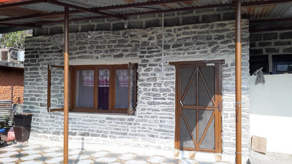 HIMALAYAN AAMA APARTMENT في بوخارا: منزل حجري مع نافذتين وباب