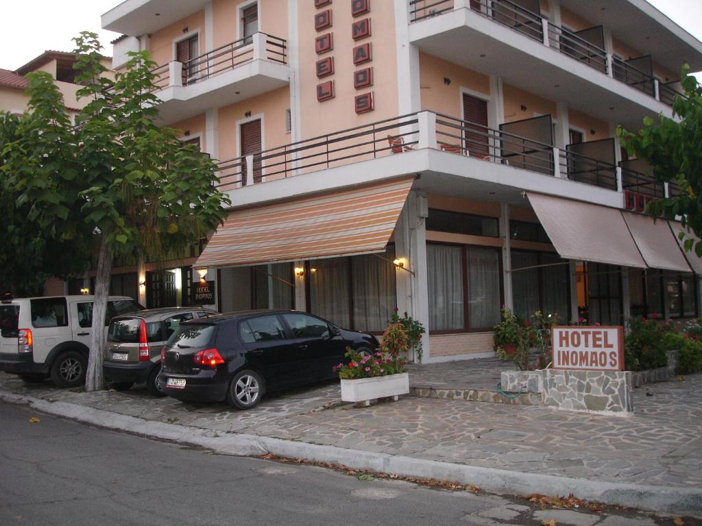 Hotel Inomaos في أوليمبيا: فندق فيه سيارات تقف امام مبنى