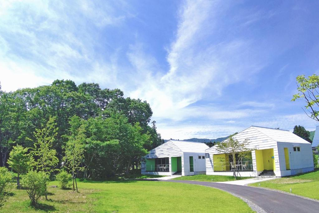 dois edifícios brancos e amarelos num campo de relva em Holiday House Green Garden em Gujo