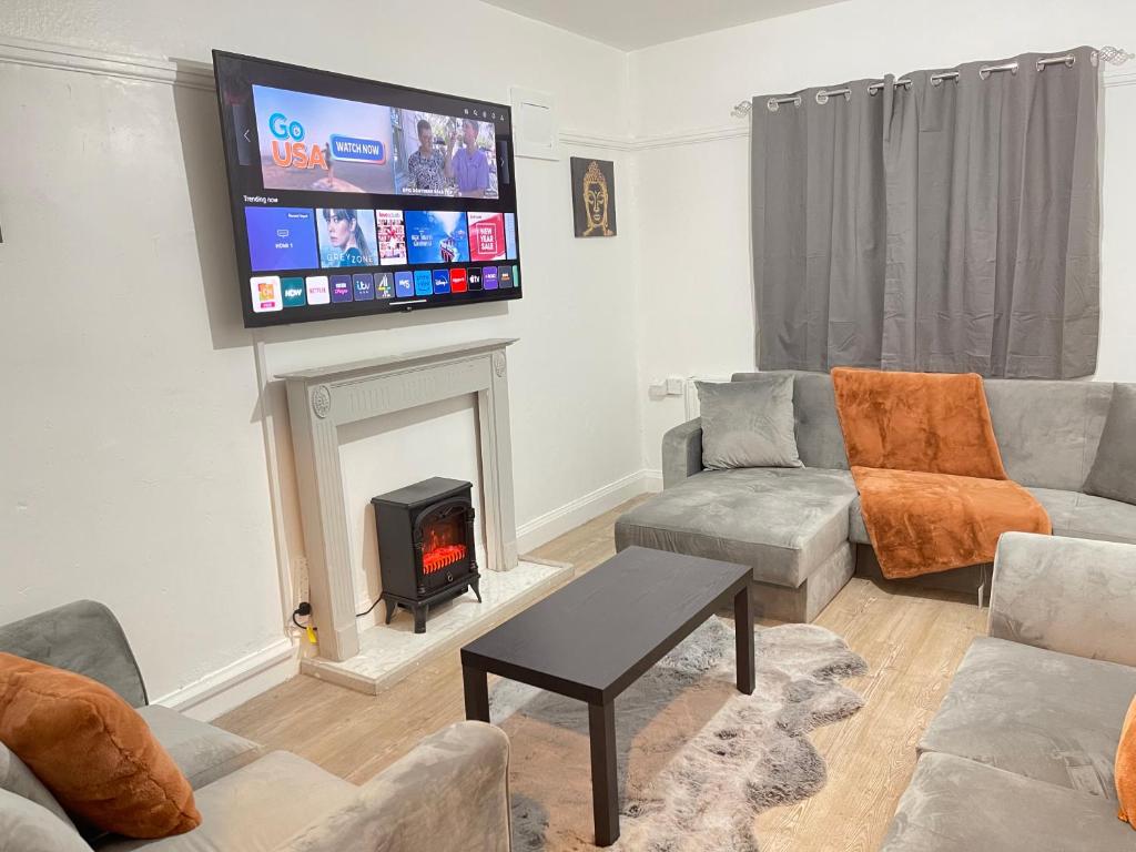 uma sala de estar com lareira e uma televisão de ecrã plano em Hometel Hidden Gem Large Comfy Home Can Sleep 14 em Braunstone