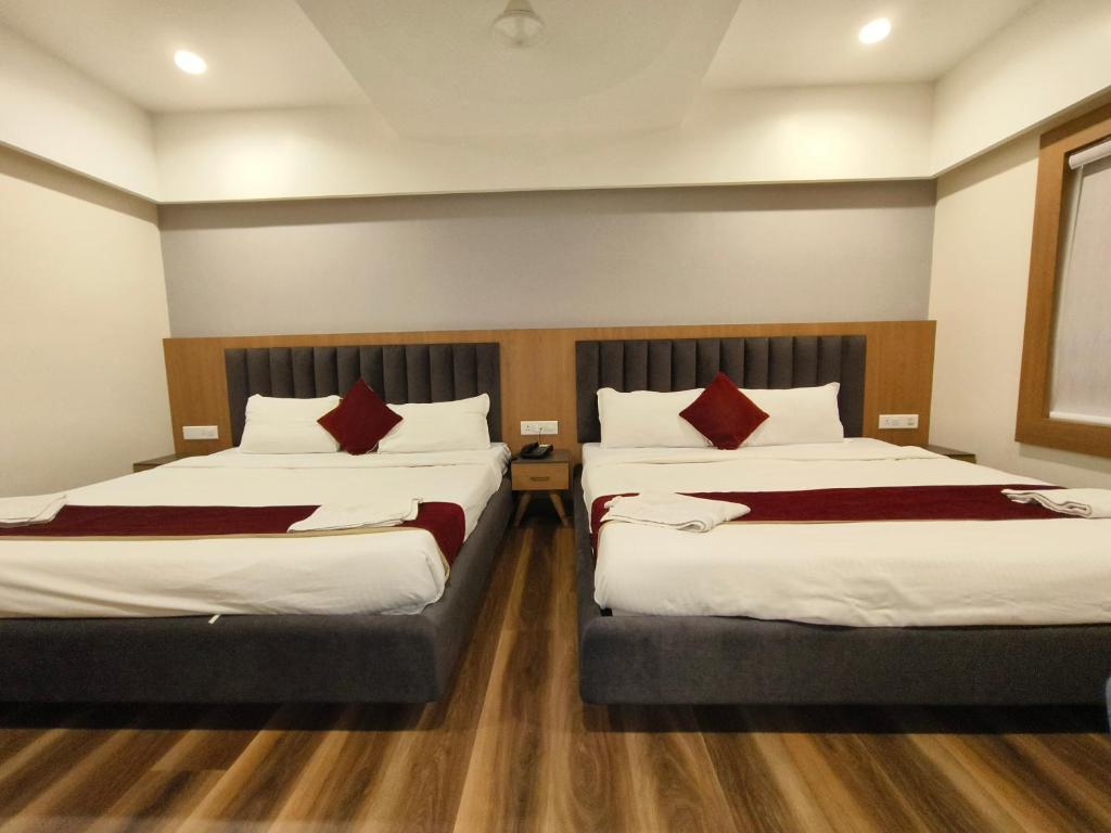 a hotel room with two beds with red pillows at Hotel welcome somnath in Somnath