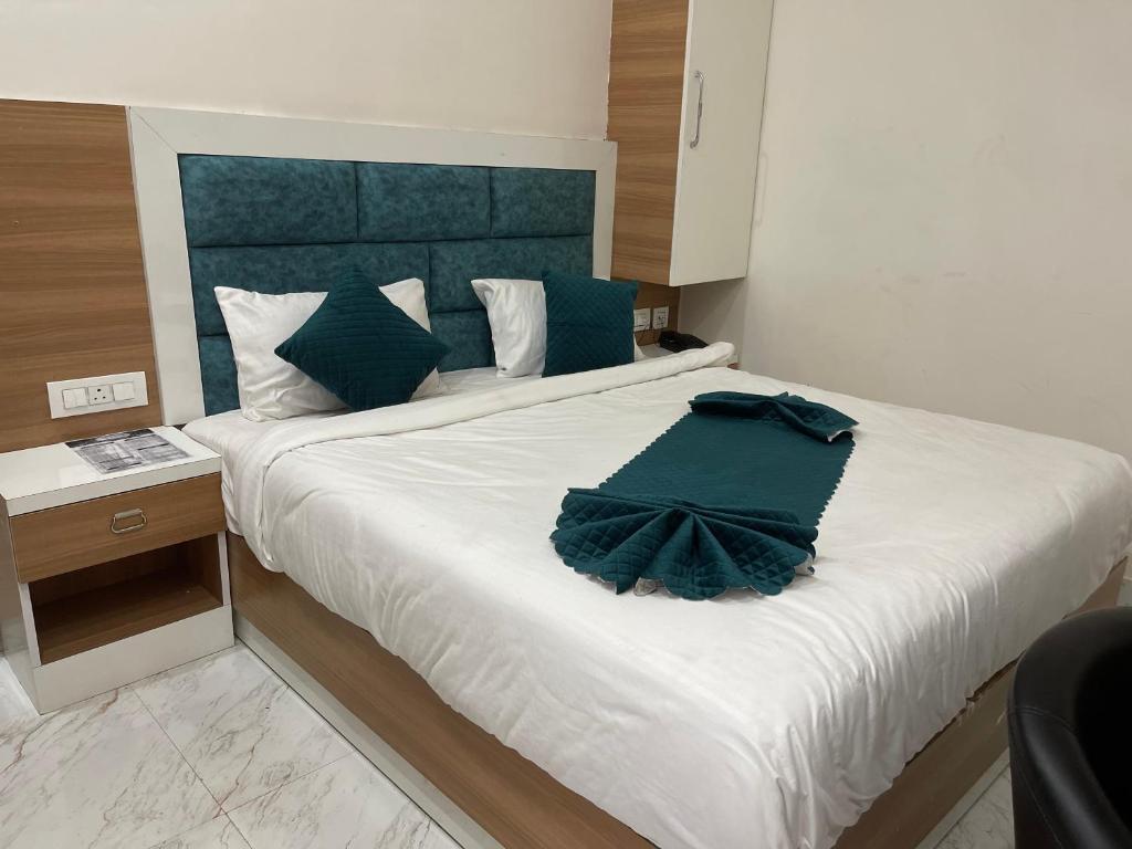 a bedroom with a large white bed with a blue headboard at Hotel Sundram in Zirakpur
