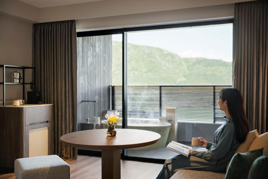 eine Frau in einem Zimmer mit einem Tisch und einem Fenster in der Unterkunft Laforet Hakone Gora Yunosumika in Hakone