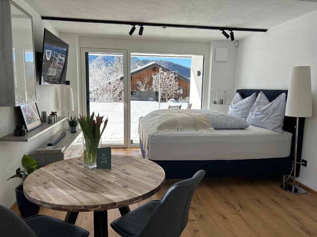 a bedroom with a bed and a table and a window at place2be - exclusive apartment in Faistenau