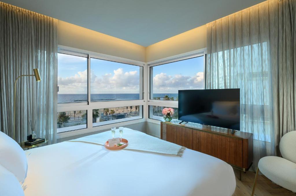 a bedroom with a large white bed and a large window at Jewel TLV Hotel in Tel Aviv