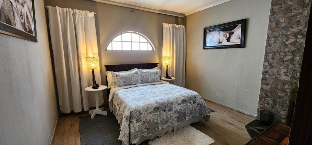 een slaapkamer met een bed met 2 lampen en een raam bij Cielo Guestfarm in Swartruggens