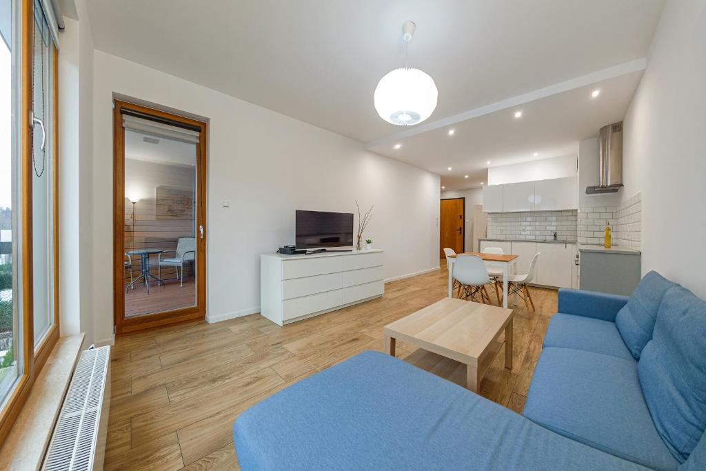 a living room with a blue couch and a kitchen at Beach&Nature - Bursztynowa in Gdańsk