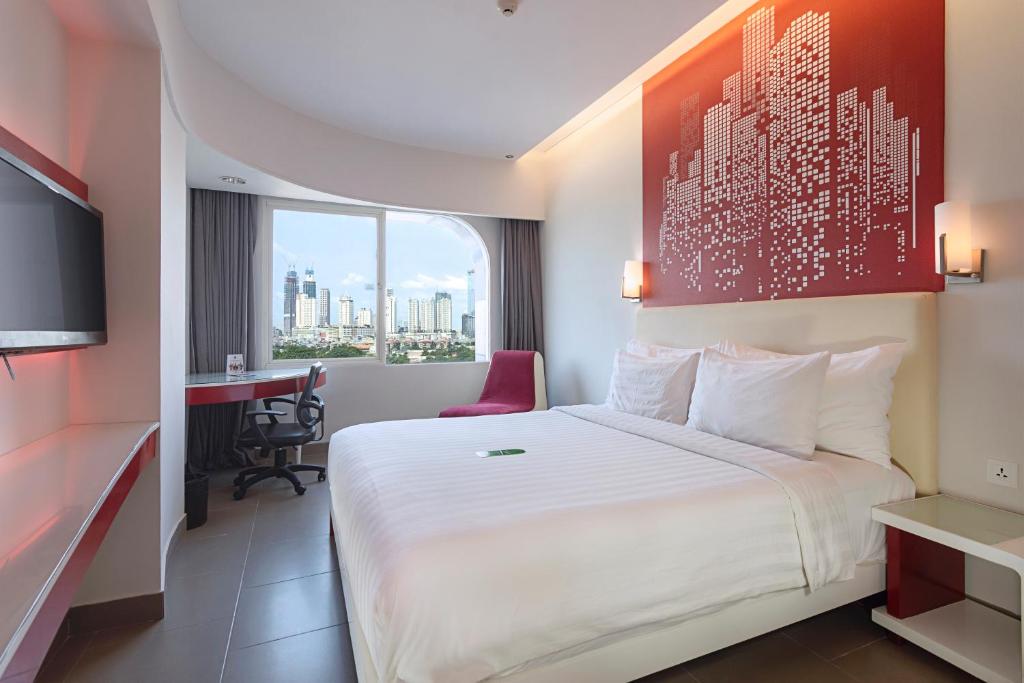 ein Hotelzimmer mit einem großen Bett und einem Schreibtisch in der Unterkunft Blue Sky Hotel Petamburan in Jakarta