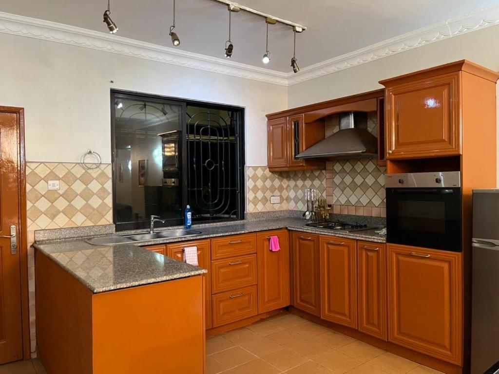 a kitchen with wooden cabinets and a sink and a refrigerator at Rose house in Dar es Salaam