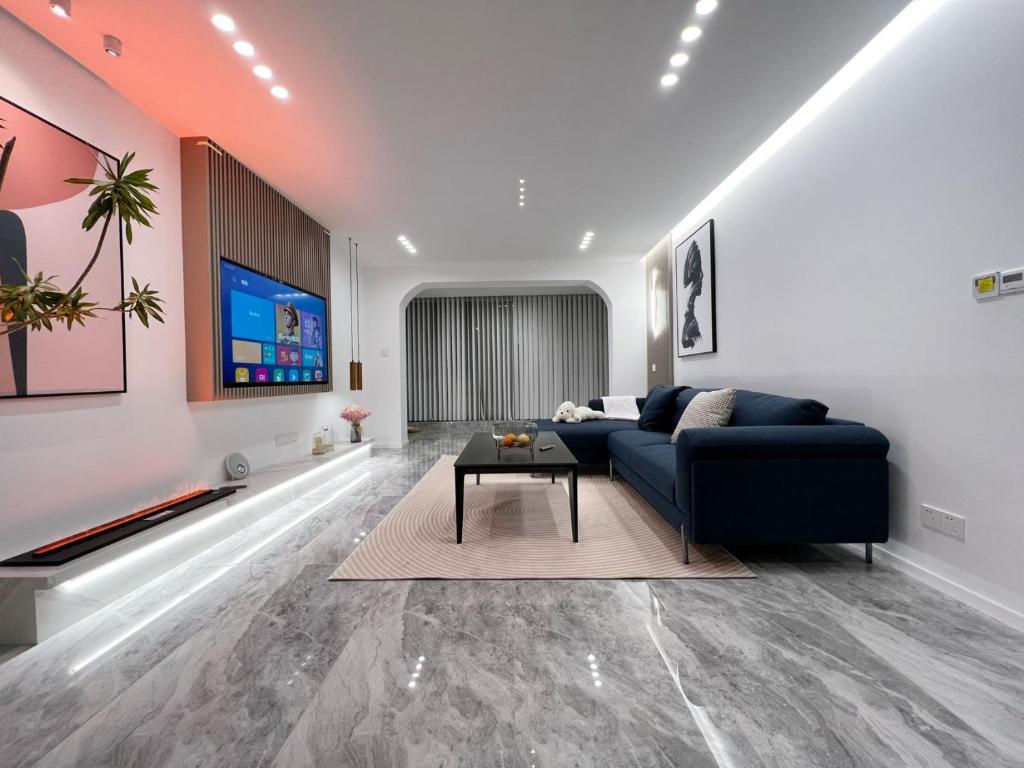 sala de estar con sofá azul y TV en Shanghai Jing'an Modern Luxury Mansion 3 Bedrooms Near Metro & Attractions, en Shanghái
