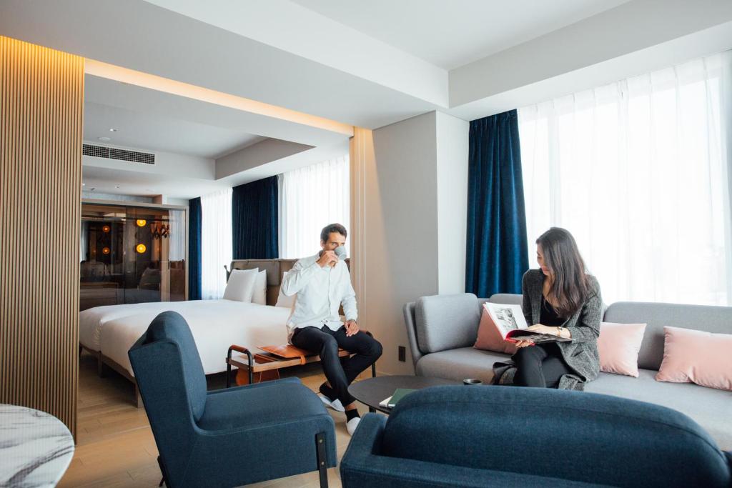NOHGA HOTEL UENO TOKYO في طوكيو: رجل وامرأة يجلسون في غرفة في الفندق