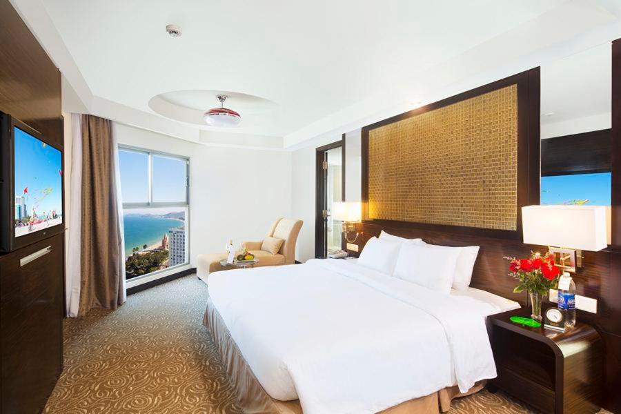 a bedroom with a large white bed and a large window at Havana Nha Trang Hotel in Nha Trang