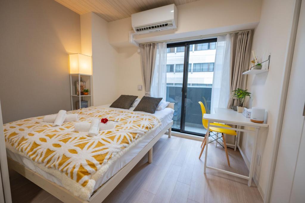 a bedroom with a bed and a desk and a window at Hotel Story Namba in Osaka