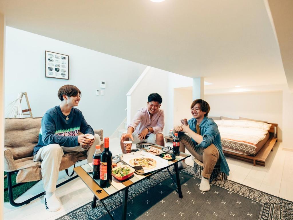 um grupo de pessoas sentadas à volta de uma mesa numa sala de estar em YOUR ROOM Kumamoto Sta little 201 Vacation STAY 75222 em Kumamoto
