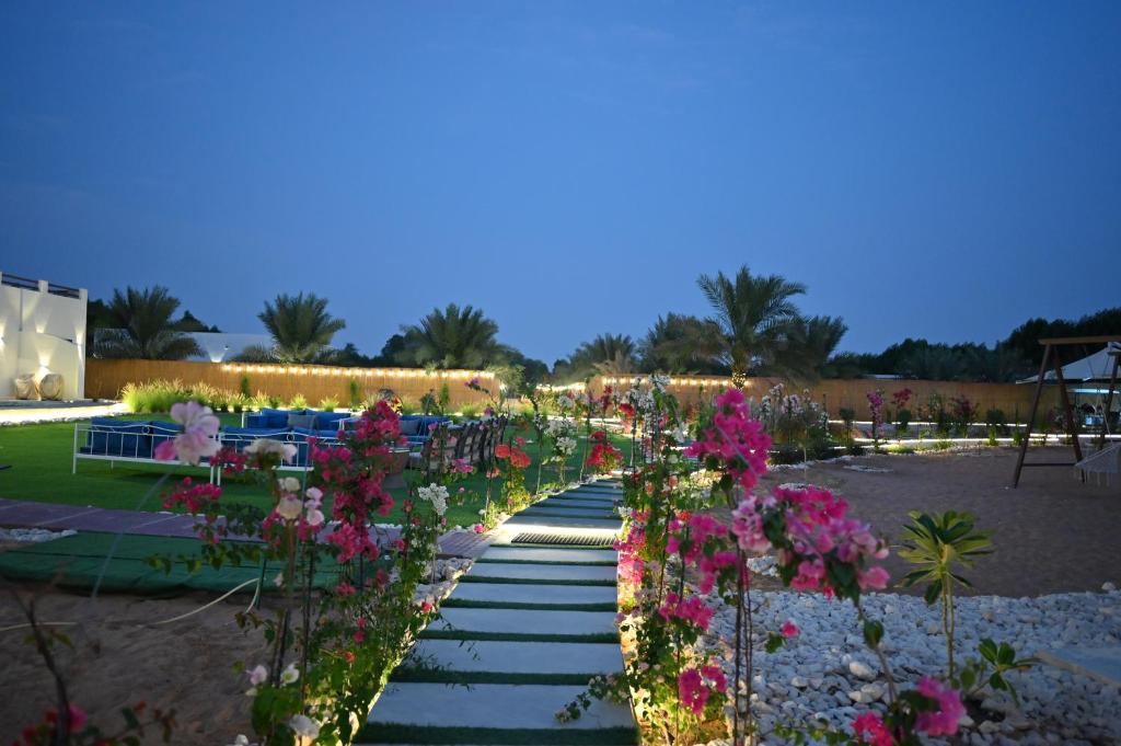 a pathway with flowers in a garden at night at Damas Resort in Mezairaa