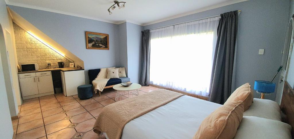 a bedroom with a bed and a chair and a window at Blue Door in Boksburg