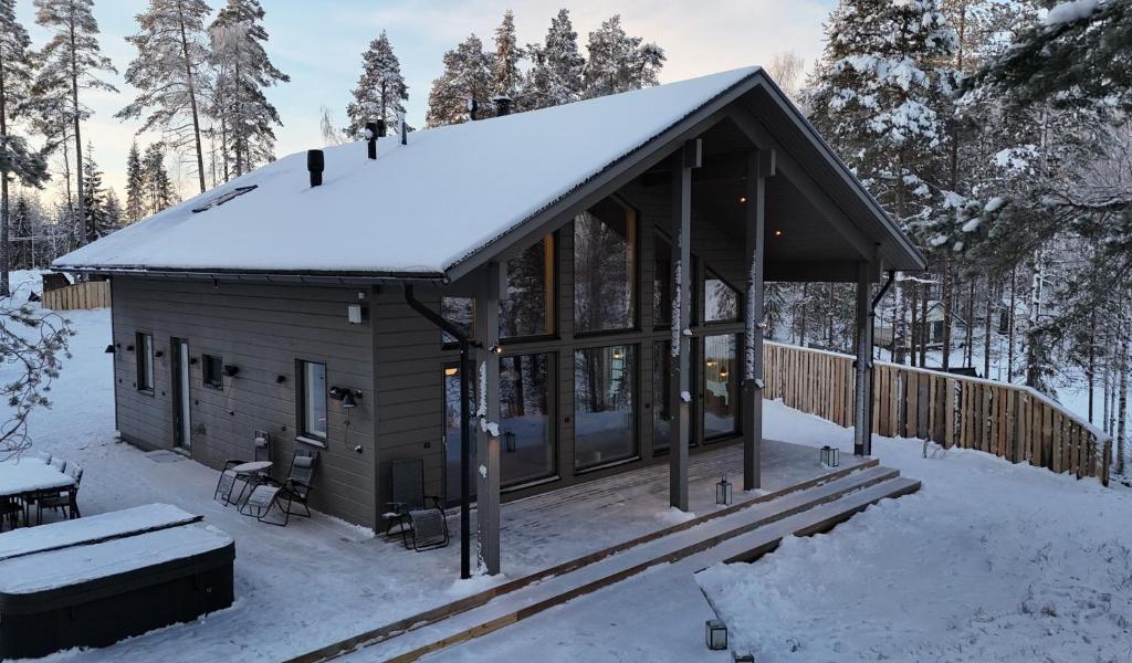 une cabane avec un toit couvert de neige dans la neige dans l'établissement Villa Pöylikki, à Rovaniemi