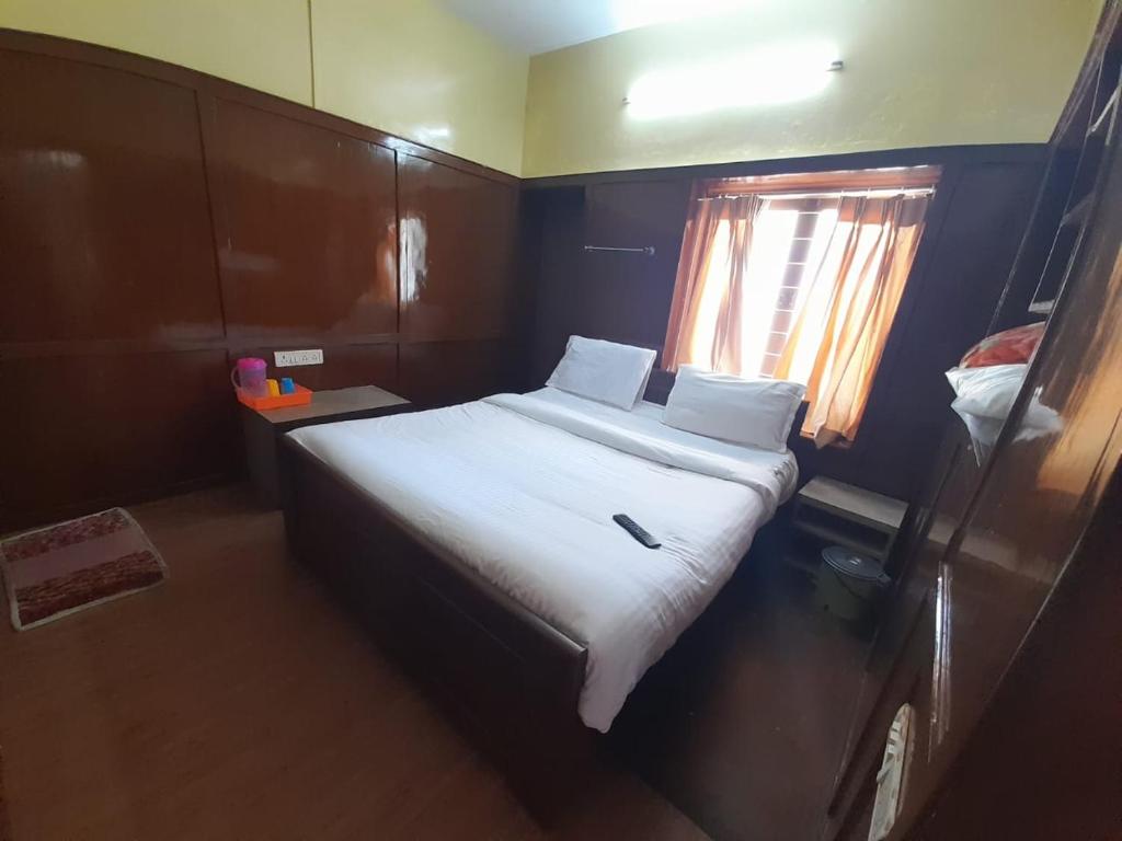 a bedroom with a bed with white sheets and a window at A2 Home Stay in Kodaikānāl
