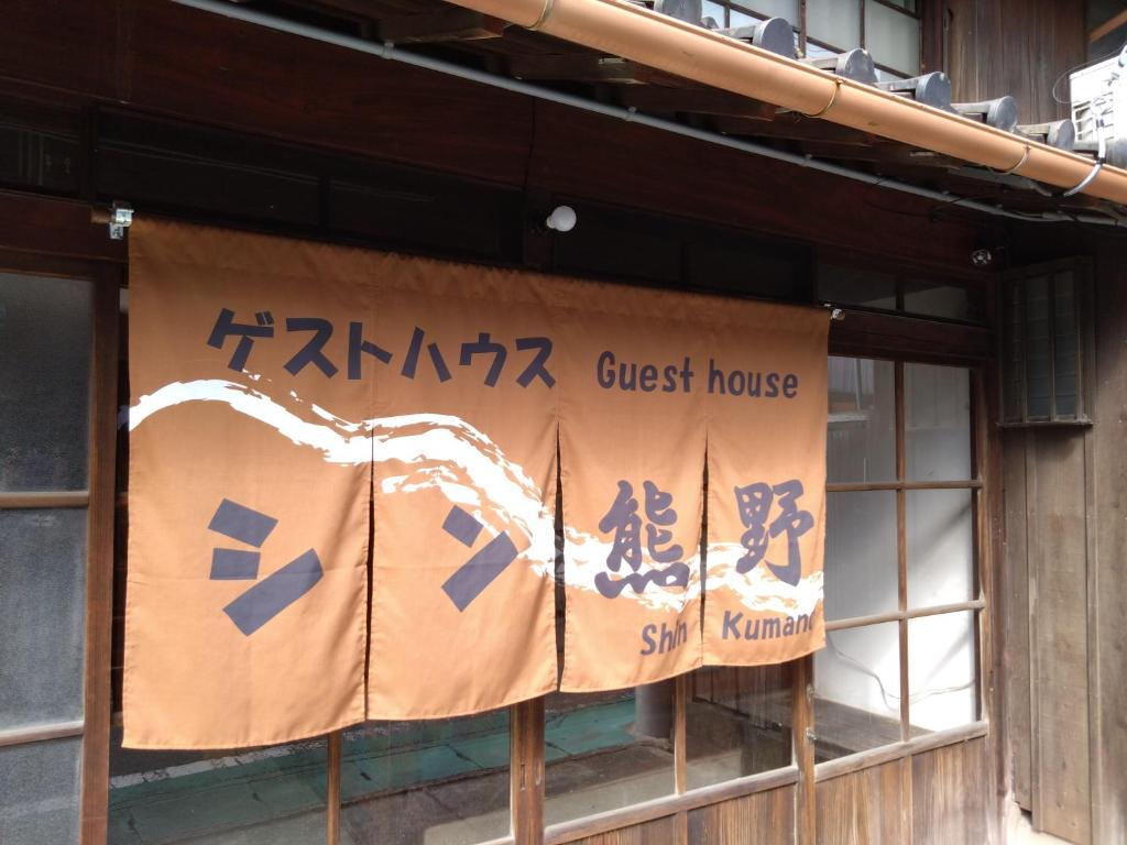 un letrero para una casa de huéspedes al lado de un edificio en ゲストハウス　シン熊野 en Tanabe