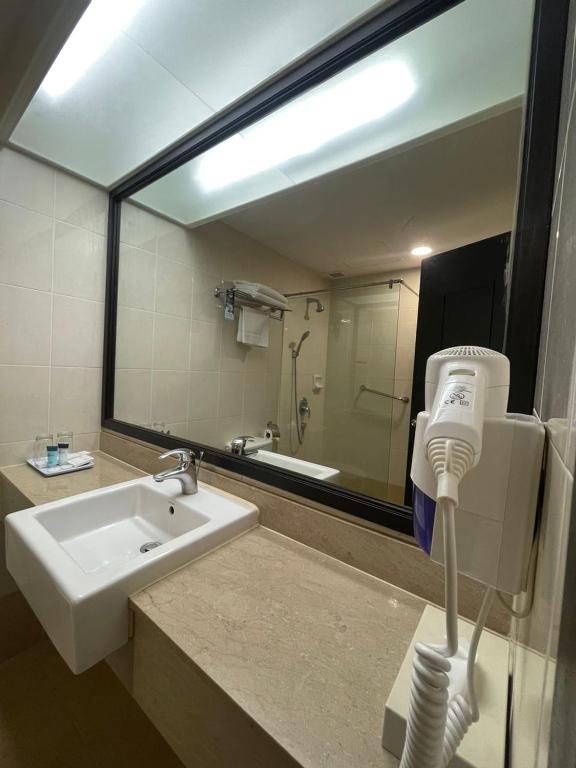 a bathroom with a sink and a mirror and a hair dryer at Flamingo Hotel by the Beach, Penang in George Town