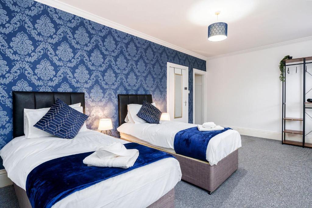 two beds in a room with blue wallpaper at Four Bedroom City Centre Large Derby House Contractors Leisure in Derby