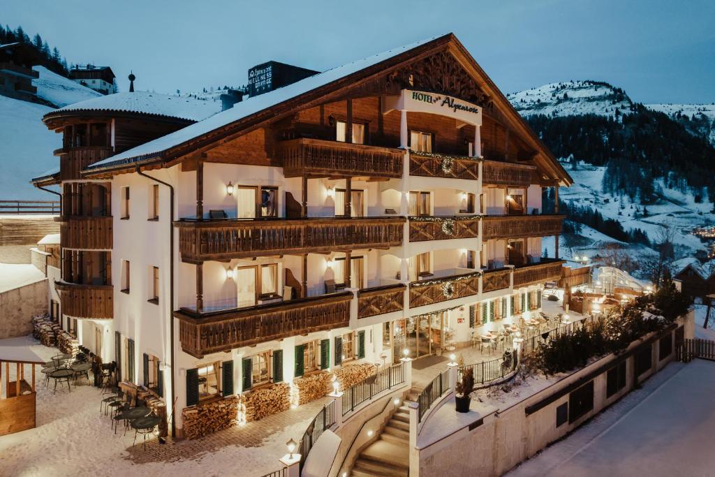 a hotel with a snow covered mountain in the background at Hotel Alpenrose in Arabba