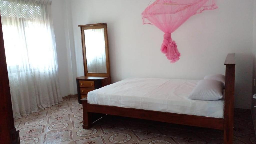1 dormitorio con 1 cama con sombrilla rosa en la pared en Ramya Villa, en Galle