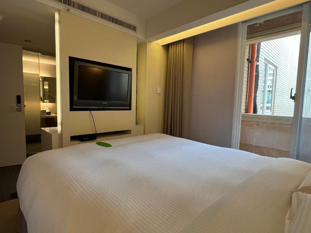 a bedroom with a white bed and a flat screen tv at 台北馥華商旅 松江館 in Taipei